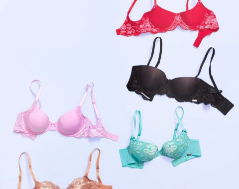 Red, black, pink, teal, and beige bras on a light blue surface.
