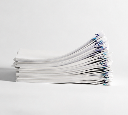 A stack of white papers with paperclips on a white surface.