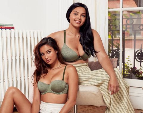 Two women modeling light green bras, one sitting, one standing.
