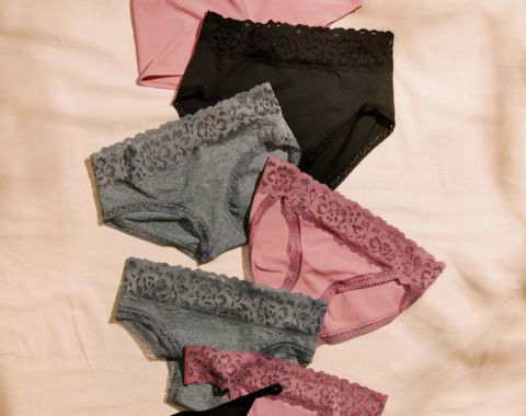 Assortment of women's lace-trimmed briefs in pink, black, and grey.
