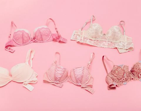 Various pastel-colored bras with lace detailing on a pink background.