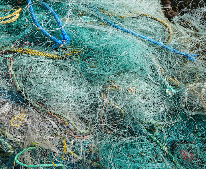 A pile of tangled blue, green, and white fishing nets.