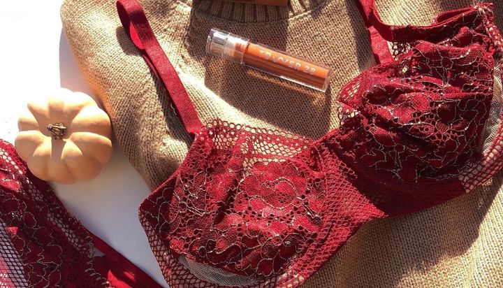 A red lace bra and lipstick tube with "OVER 28" on a sweater.