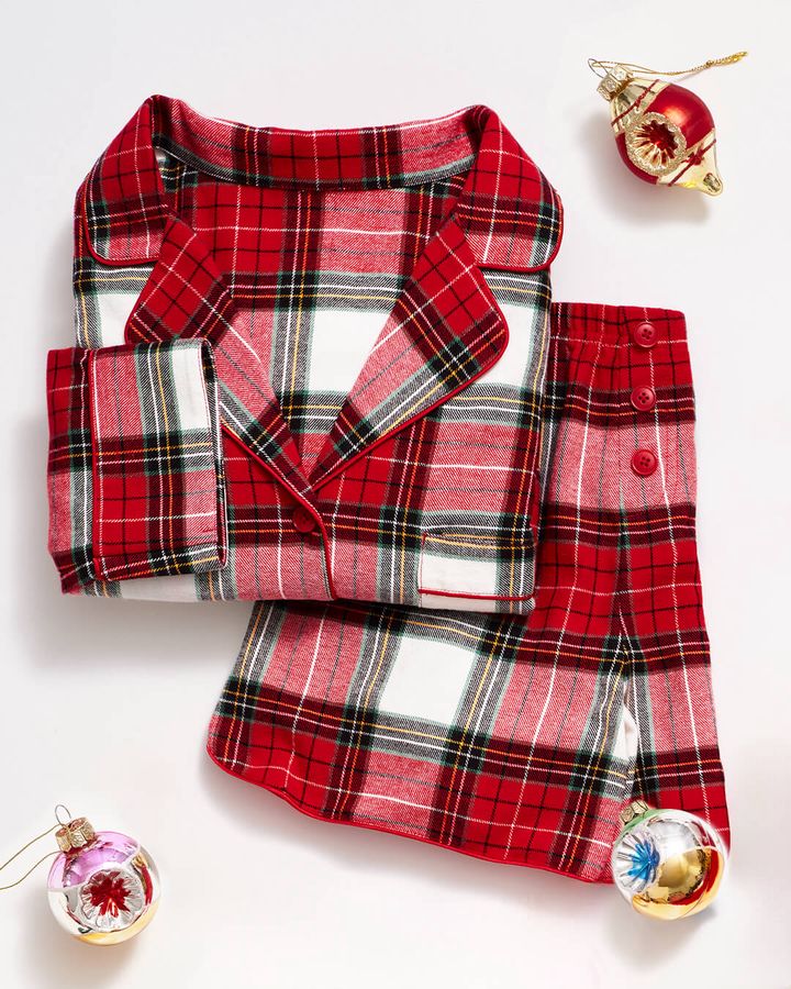 Folded red plaid pajama set with white and green accents and ornaments.