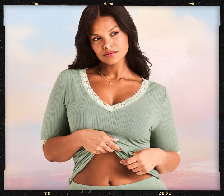 Woman modeling a green long-sleeved top with lace trim.