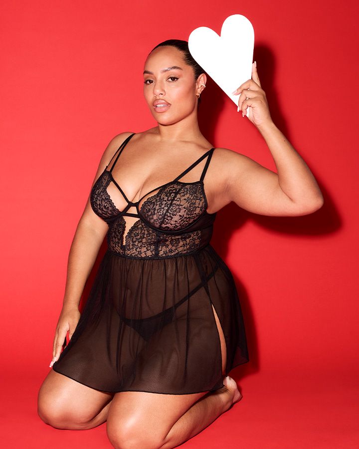 A confident woman models a black lace and sheer babydoll.