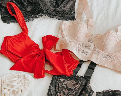 A collection of lingerie, including a red bustier, black, and beige bras.