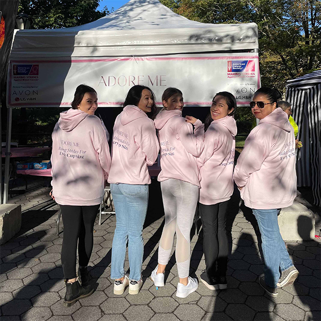 Five women in pink "ADORE ME" hoodies for breast cancer awareness.