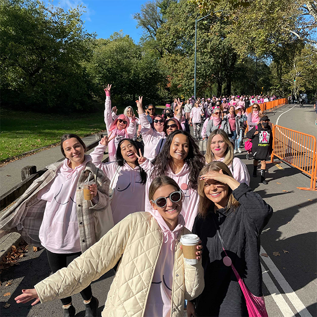 Group of women in pink shirts walking in a park.