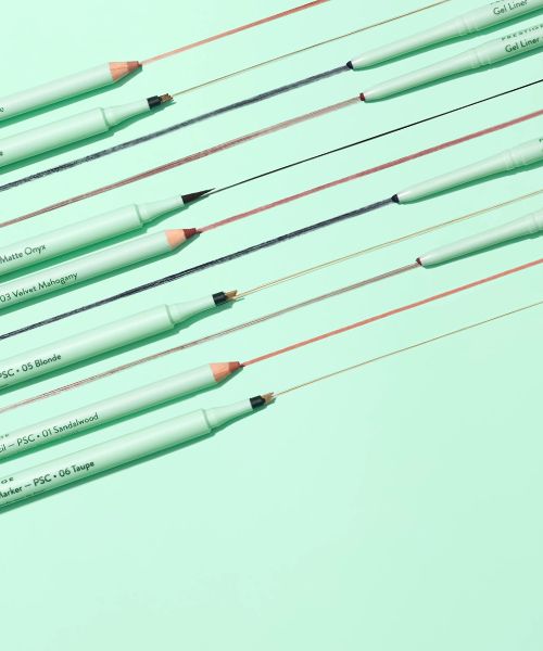 Various Prestige brand brow and eyeliner pencils on a light green surface.