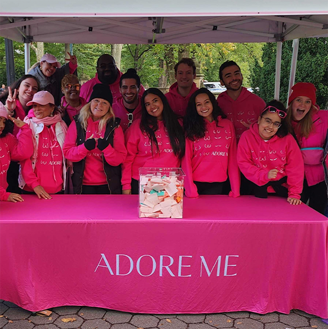 Adore Me staff at an event with a pink table and banner.