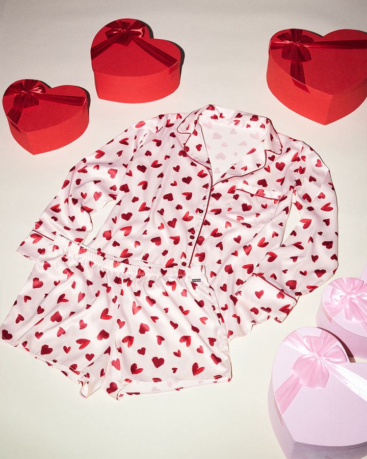 White satin pajamas with red hearts, surrounded by heart-shaped gift boxes.